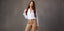 Woman wearing a white shirt and beige high-waisted cargo pants, posing against a neutral-toned background.